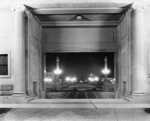 Night view of the Civic Center illuminated with streetlamps and framed by the Greek Theatre in Denver, Colorado. Signs read: "Miller Tires" and "Willy [Ove]rland Inc." (circa 1910-1920)