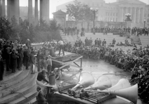 Men crowd Civic Center amphitheater in Denver, Colorado, at a Mining Institute contest. Miners on wooden platforms swing hammers; loudspeakers are in the foreground. (09-29-1936)