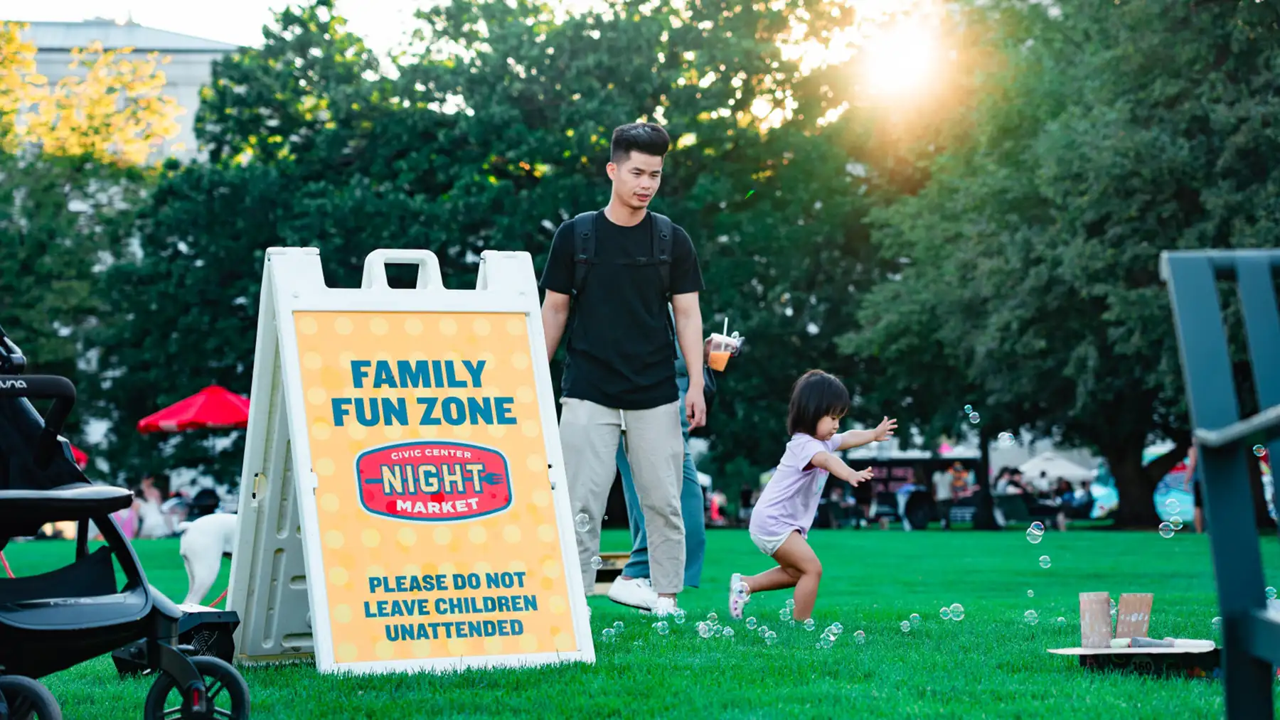 A poster reads "Family Zone" while a man watches his young daughter playing with bubbles