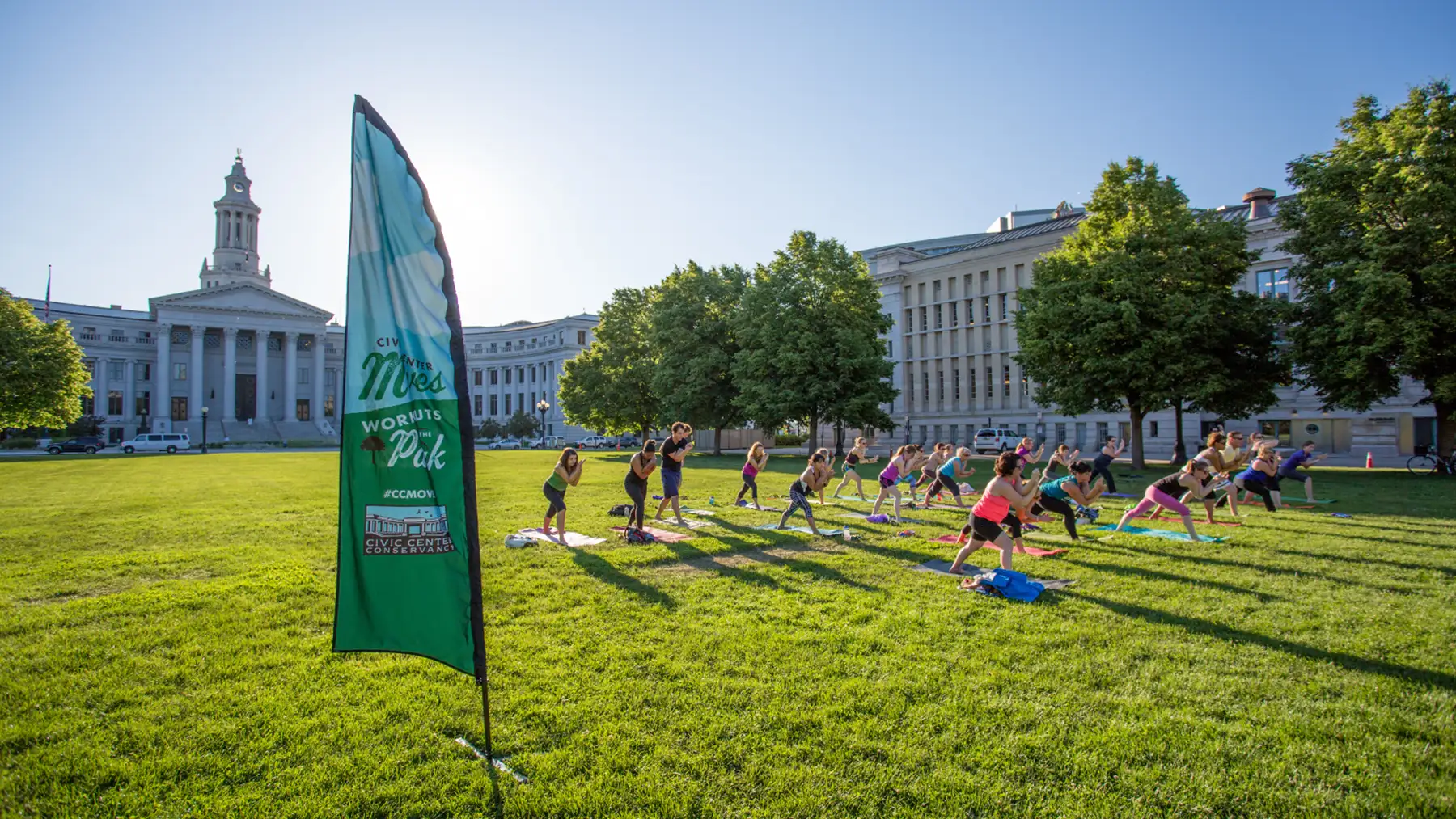 A group gathers at Civic Center Park on a sunny day to do yoga in the grass